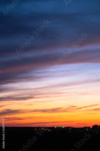 sunset sky blue-orange colors with dramatic clouds against the bokeh lights of the city © Daria