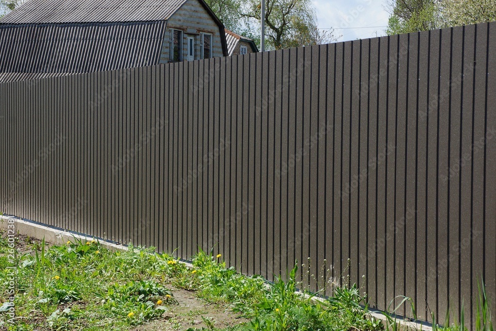 long gray brown metal fence outside in green grass long gray brown metal fence outside in green grass