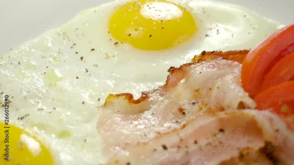 English breakfast. Close-up shot of three fried eggs and bacon serving on a white plate. Slow motion. HD English breakfast. Close-up shot of three fried eggs and bacon serving on a white plate. Slow motion. HD