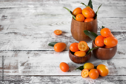 Fresh kumquats with leaves in wooden cups on the white table © kcuxen