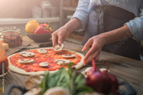 Pizza art. The process of making pizza. Raw dough for pizza with ingredients and spices on table. Traditional Italian pizza and vegetables on a dark wooden background. Pizza menu. Soft focus.