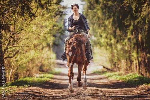 young woman riding on galloping horse with cordeo in the morning in spring forest