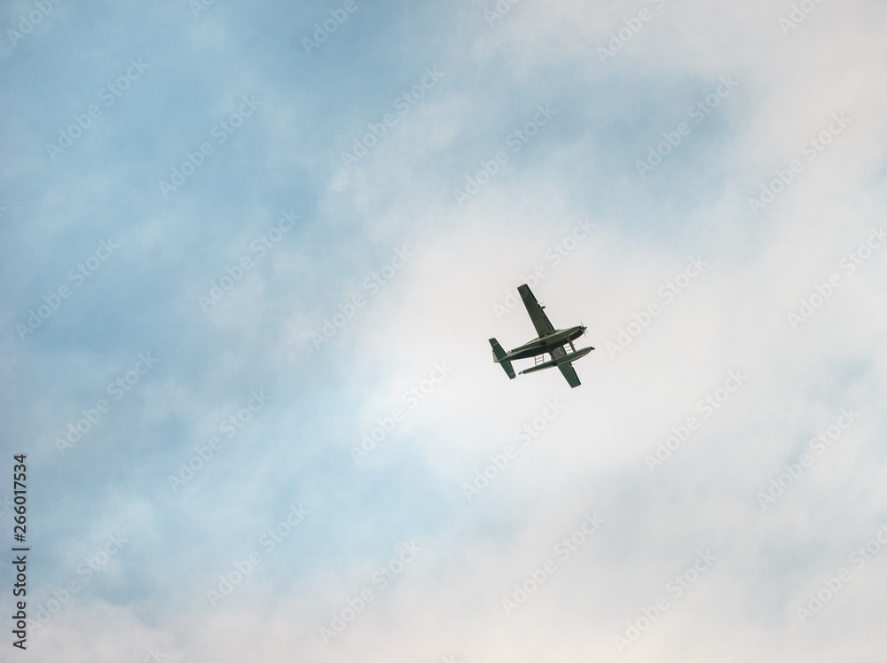 Single engine airplane flies across partially cloudy sky Single engine airplane flies across partially cloudy sky