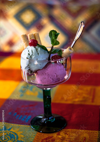 Popsicles in a glass cup with a waffle stick on a colored background