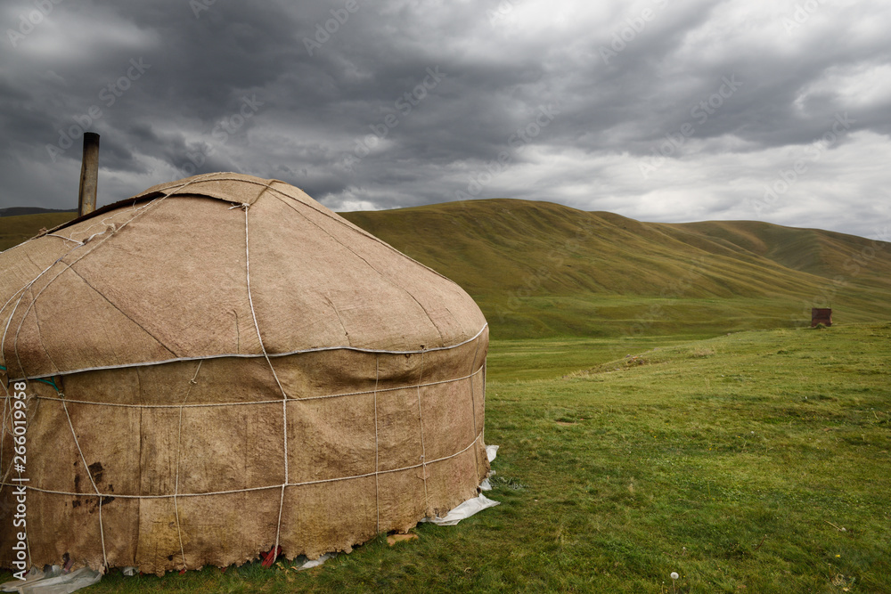 Yurt with chimney and outhouse in barren pastureland of Assy Plateau Kazakhstan