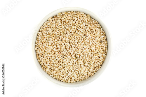 Quinoa raw seeds in white ceramic bowl on a white, top view