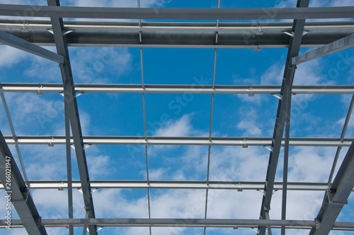 Metal frame of the new building against the blue sky with clouds