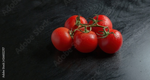 Close-up of freshly picked tomatoes on ebony background with copy space