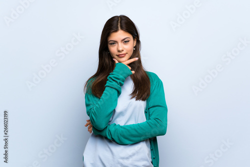 Teenager girl over blue wall thinking