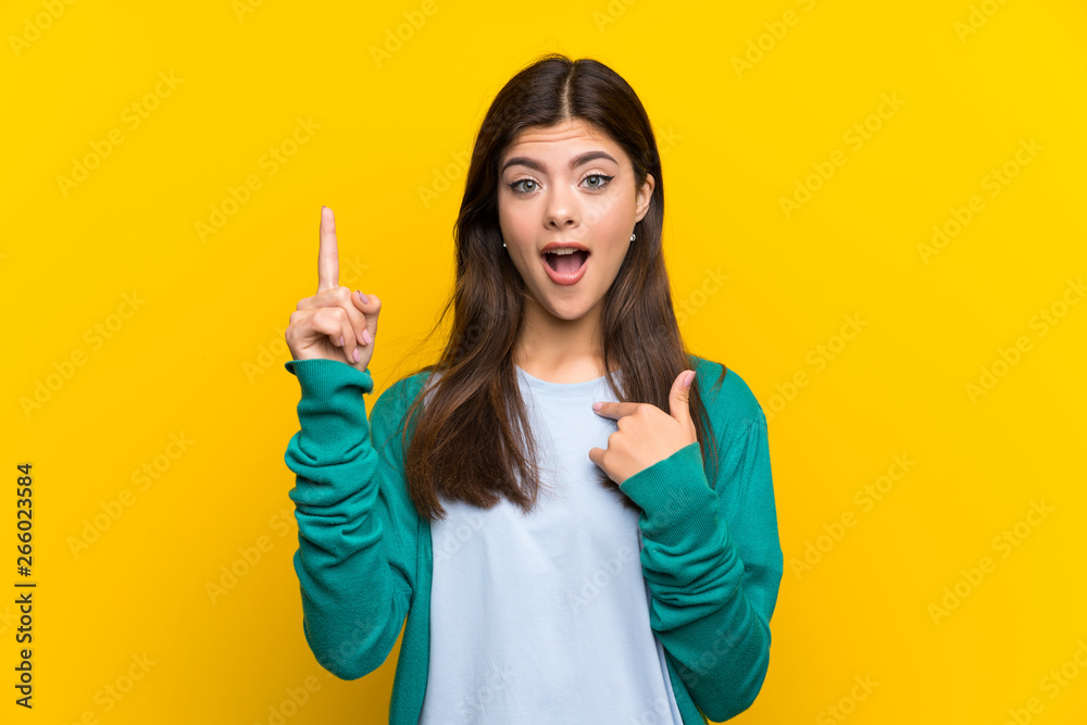 Teenager girl over yellow wall with surprise facial expression Teenager girl over yellow wall with surprise facial expression