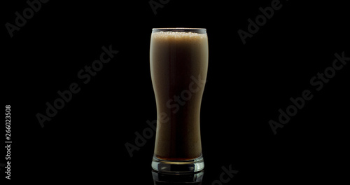 dark beer poured into a glass goblet on a black background