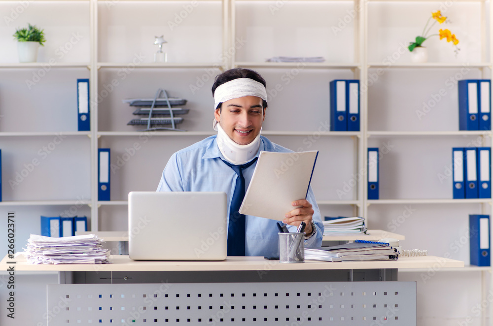 Young injured male employee working in the office Young injured male employee working in the office