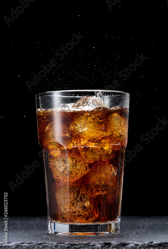 glass of cola with ice on black background