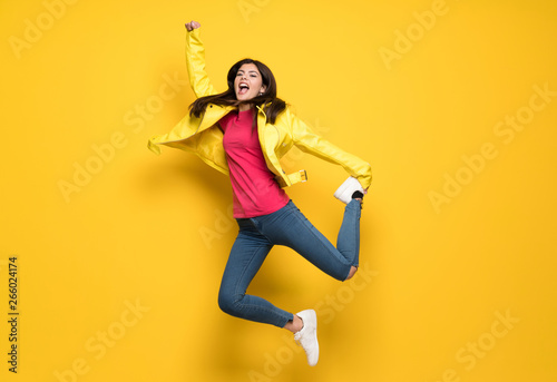 Teenager girl jumping over isolated yellow wall photo