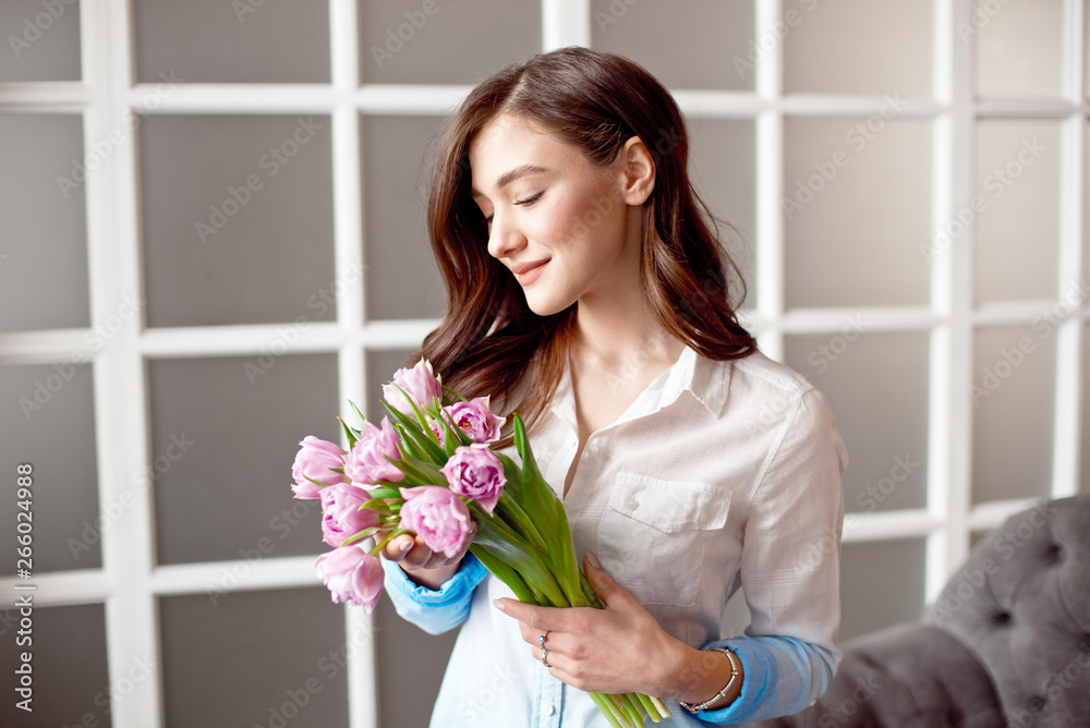 Young beautiful brunette girl holding a spring bouquet of tulips in her hands. Lifestyle Young beautiful brunette girl holding a spring bouquet of tulips in her hands. Lifestyle