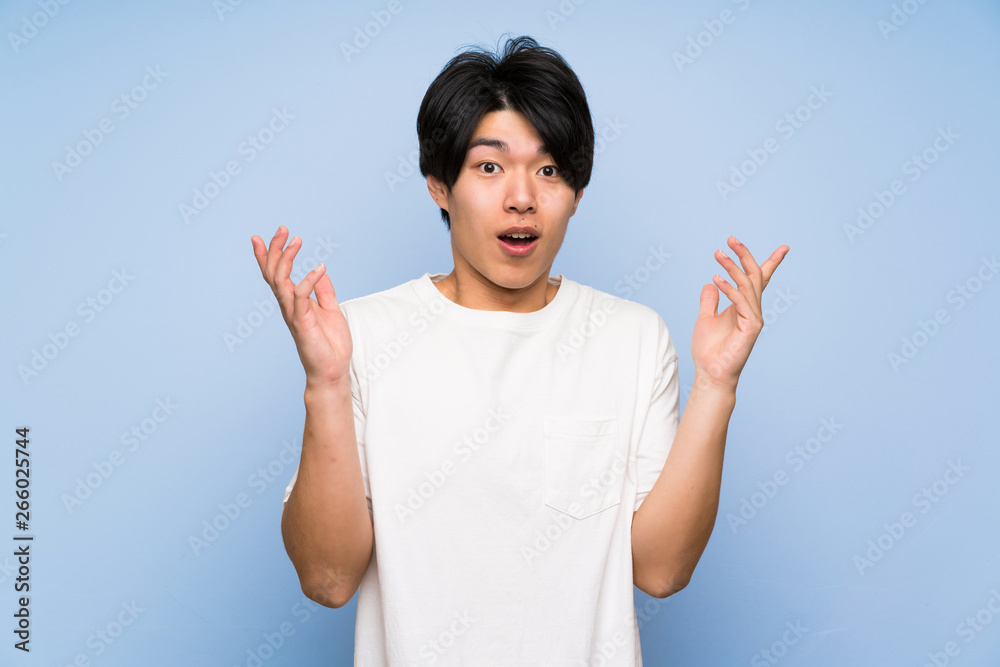 Asian man on isolated blue background with surprise facial expression Asian man on isolated blue background with surprise facial expression