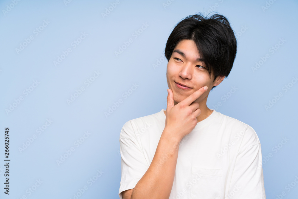 Asian man on isolated blue background thinking an idea Asian man on isolated blue background thinking an idea