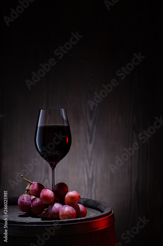 Glass of red wine and pink grapes on wooden barrel © alexlukin