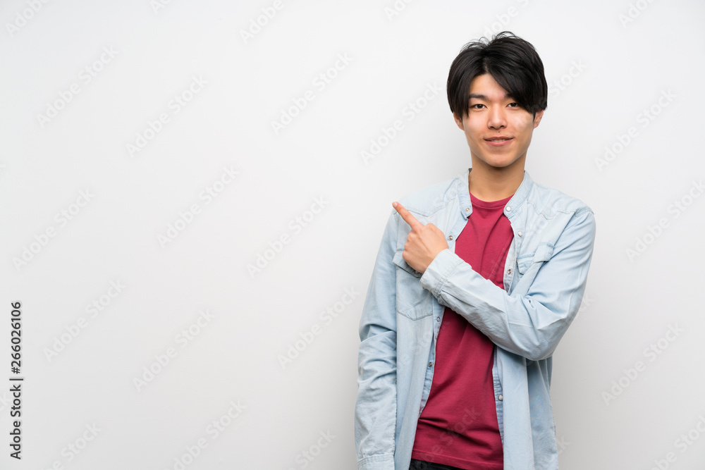 Asian man on isolated white background pointing to the side to present a product Asian man on isolated white background pointing to the side to present a product
