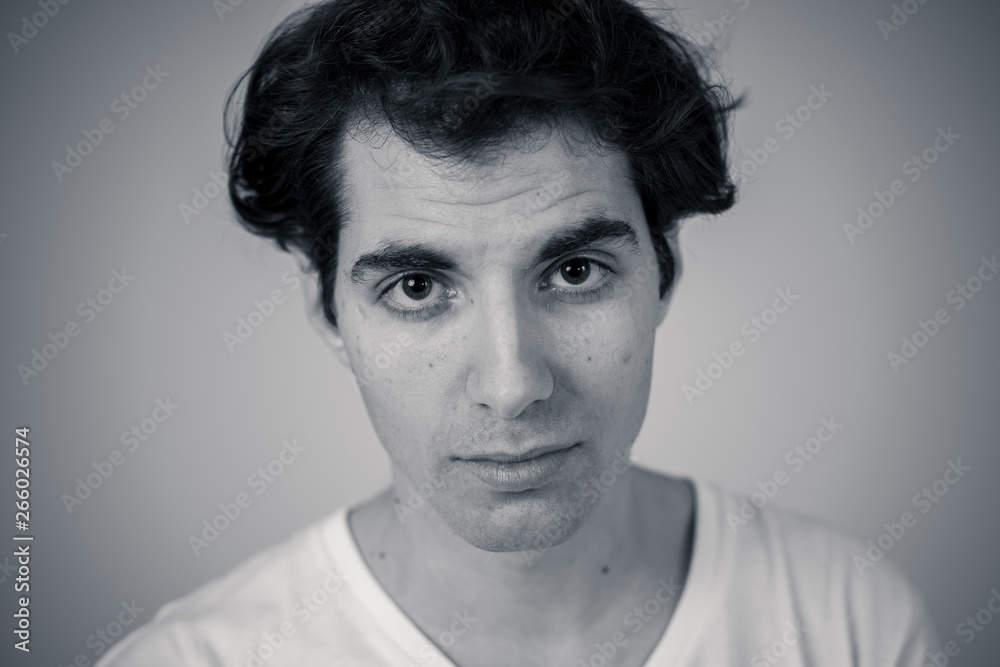 Natural portrait of young attractive man in his 20s looking and posing with neutral face expression