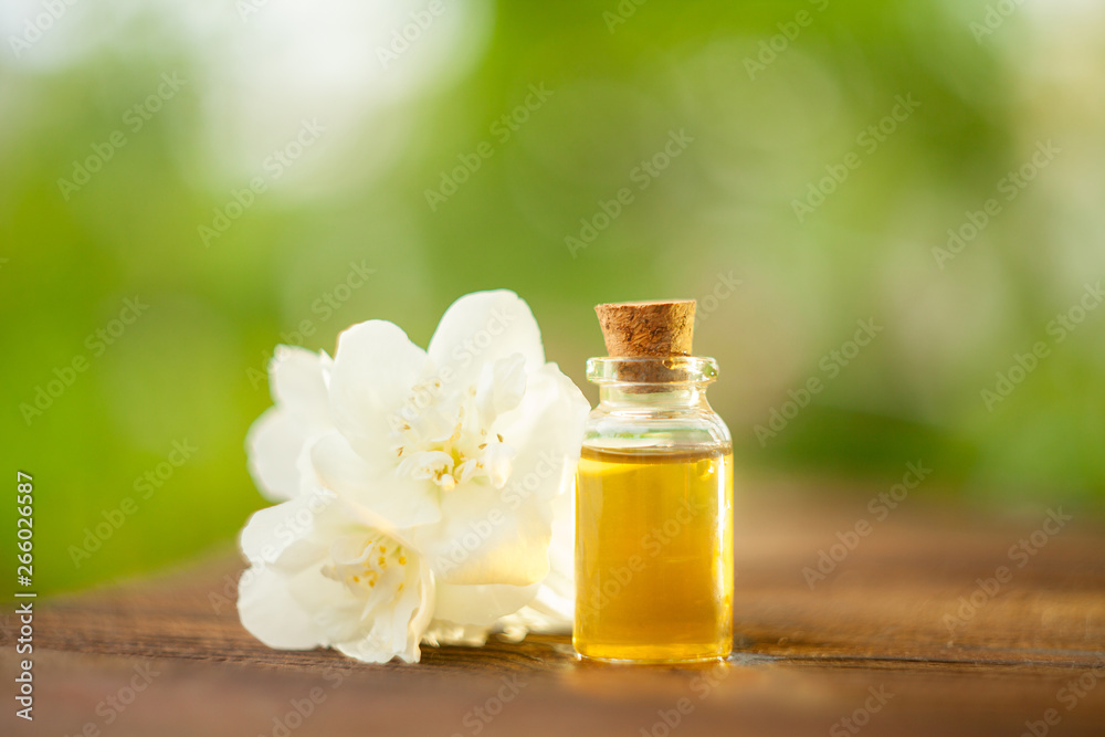 Essence of flowers on wooden background in beautiful glass jar Essence of flowers on wooden background in beautiful glass jar
