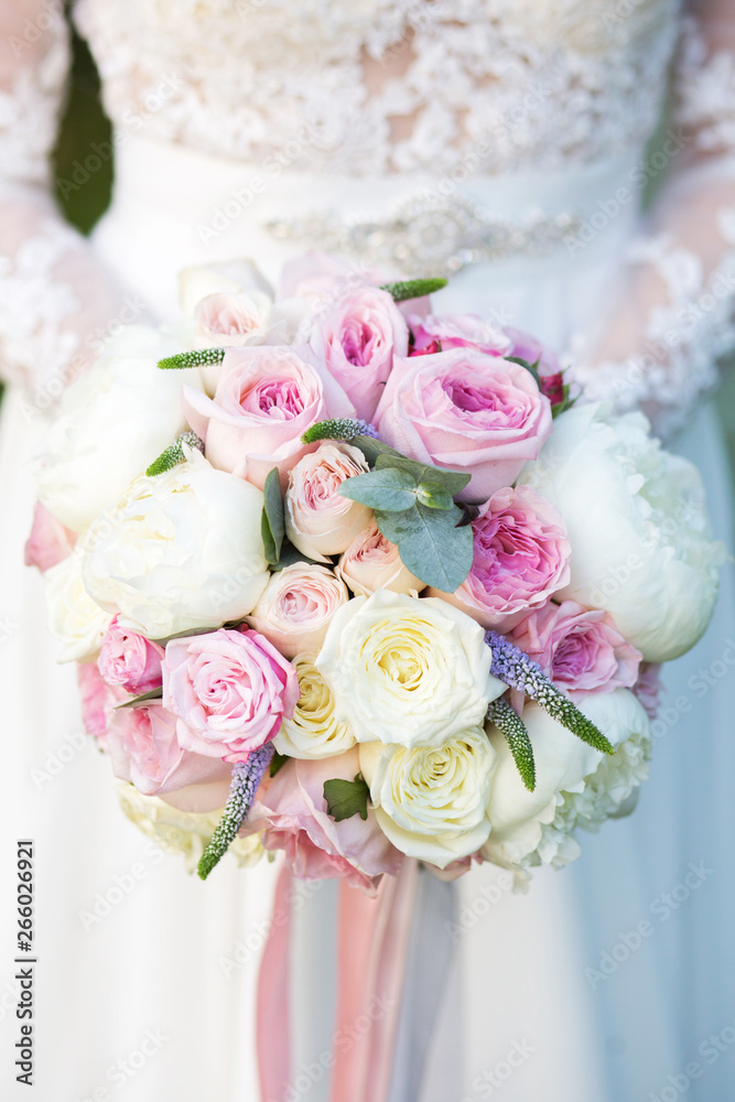 Unrecognizable bride holding a refined wedding bouquet of pink and white roses with peonies