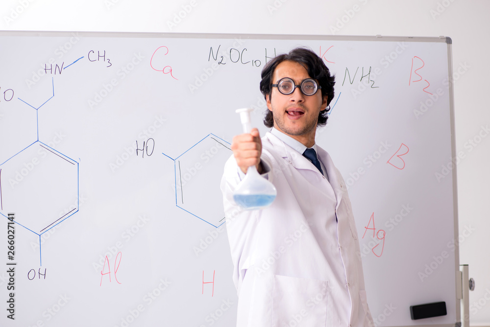 Young funny chemist in front of white board Young funny chemist in front of white board