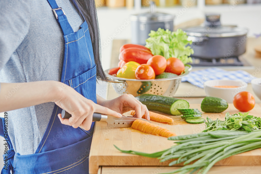 A young woman prepares food in the kitchen. Healthy food - vege A young woman prepares food in the kitchen. Healthy food - vege