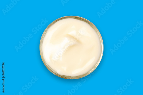 Spa cream in a glass cup placed on a blue background. Cosmetic cream camomile. Organic cosmetics with coconut on blue background top view.