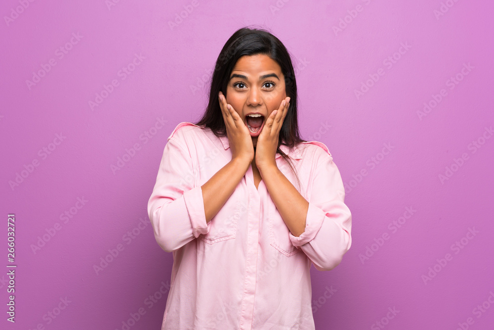 Young Colombian girl over purple wall with surprise and shocked facial expression Young Colombian girl over purple wall with surprise and shocked facial expression