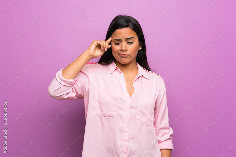 Young Colombian girl over purple wall making the gesture of madness putting finger on the head Young Colombian girl over purple wall making the gesture of madness putting finger on the head