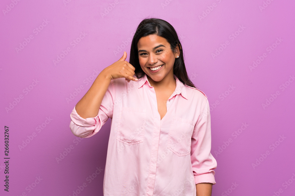 Young Colombian girl over purple wall making phone gesture. Call me back sign Young Colombian girl over purple wall making phone gesture. Call me back sign