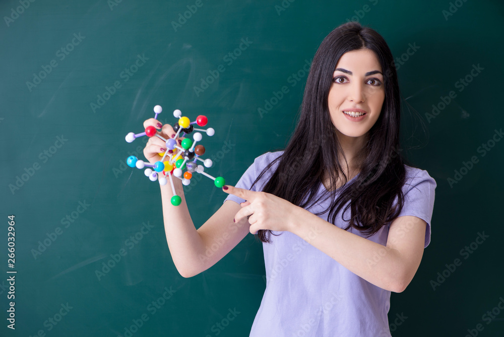 Young female teacher student in front of green board 