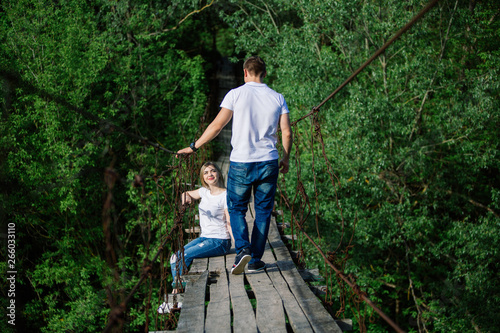  loving man and woman is sitting on the bridge.Hugging couple smiling and looking at each other outdoor in the spring.
