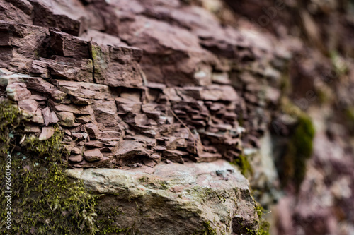 red rock wall of ravine with green moss closeup