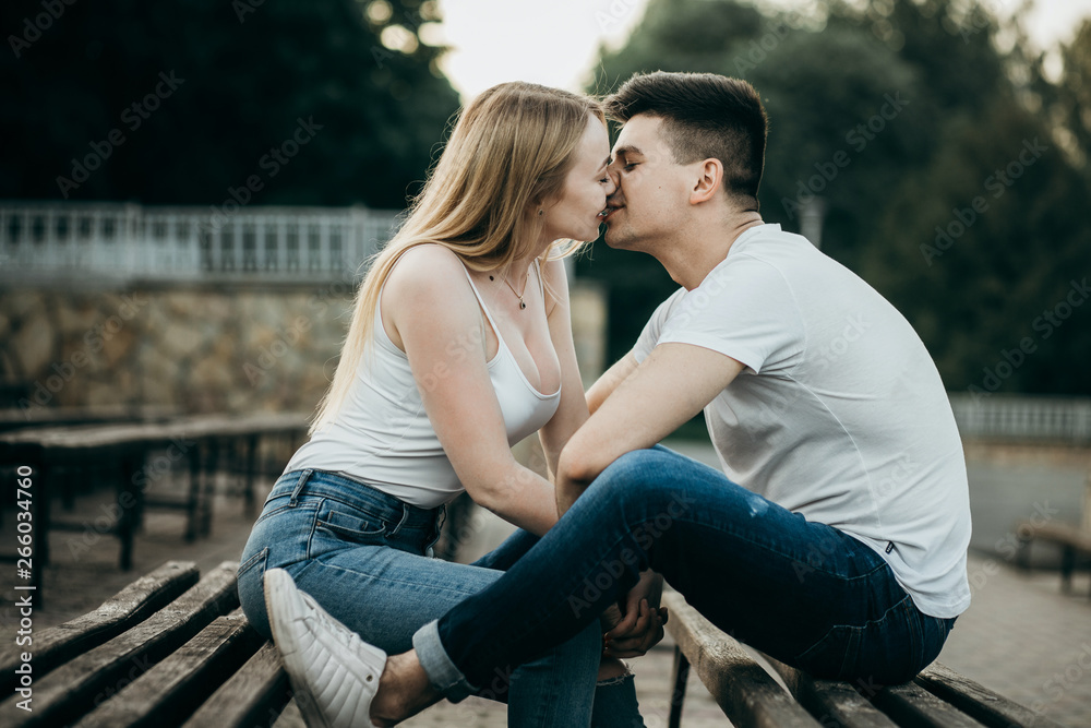 A young couple in love kissing on the bench in the park A young couple in love kissing on the bench in the park