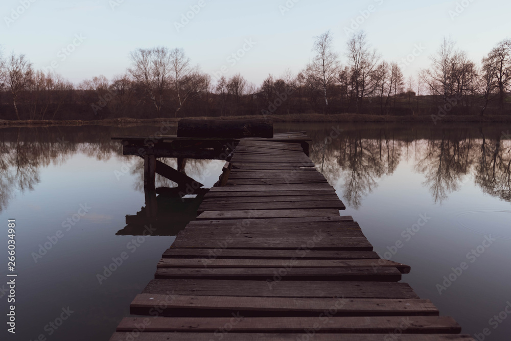Naklejka premium old wooden pier at small beautiful pond on sunset