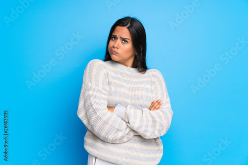 Young Colombian girl with sweater making doubts gesture while lifting the shoulders