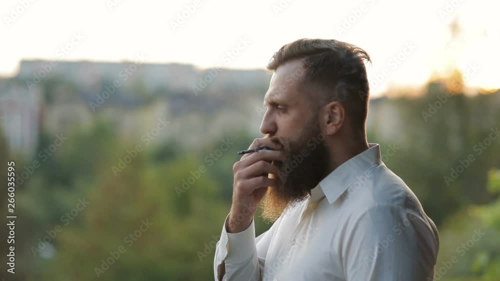 Handsome bearded man, stylish hipster male smoking cigarette outdoor Handsome bearded man, stylish hipster male smoking cigarette outdoor