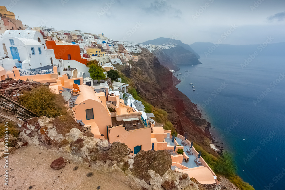 Panorama of colorful houses of Oia, red cliffs and caldera on rainy day