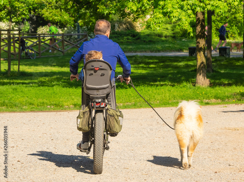 father and son cycling in the park with their dog. Milan - Italy