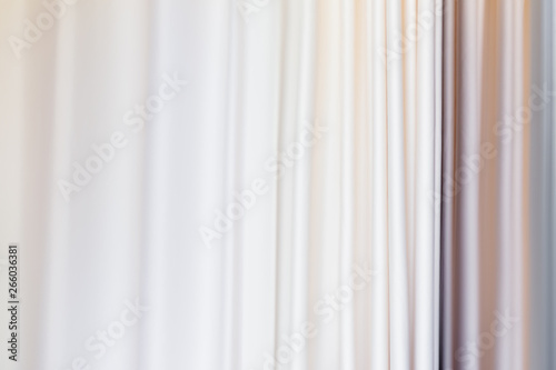 Pastel colored curtains on window. Textile folds of drapery.