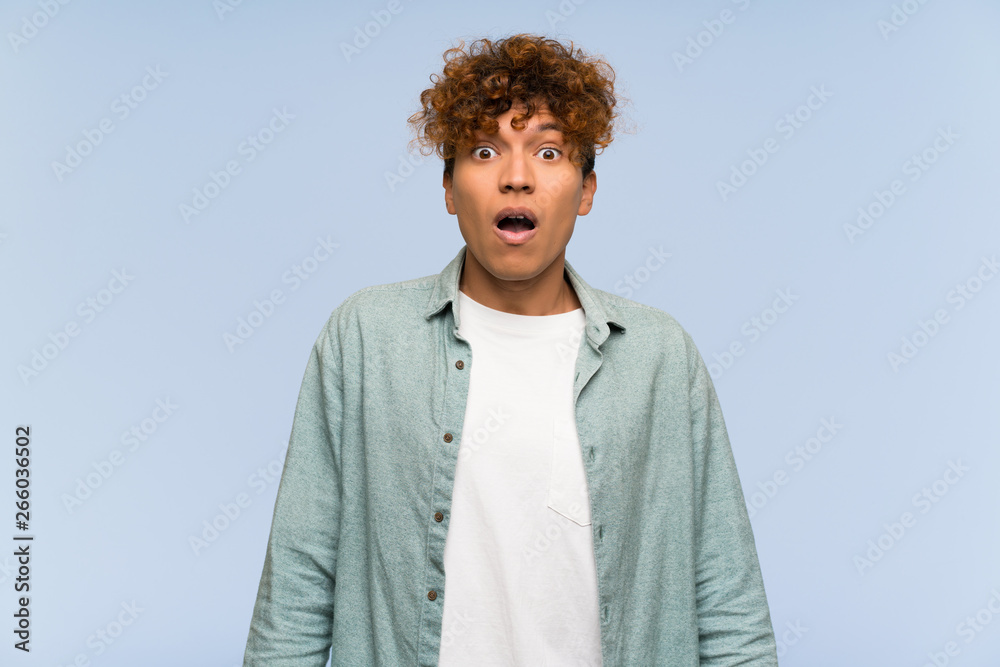 Young african american man over isolated blue wall with surprise facial expression Young african american man over isolated blue wall with surprise facial expression