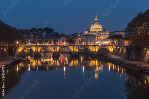 Tiber and St Peters Basilica with Aurelius Bridge or Ponte Sisto Bridge at the blue hour with lighting and reflections. Stone bridge at night over river Tiber in the historic center of Rome