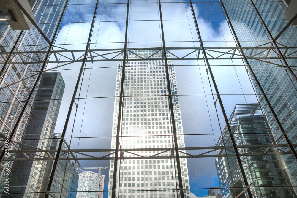 London, UK. Glass windows of the ground floor office building with beautiful reflections and  view on Canary Wharf tower