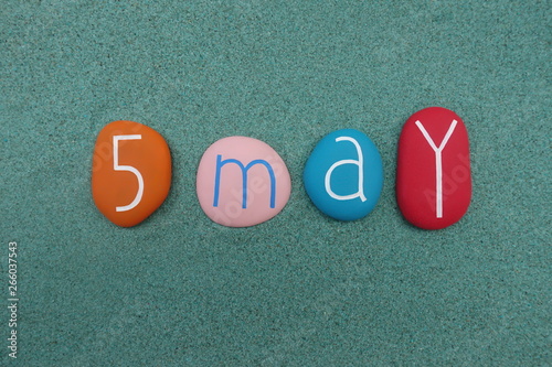 5 May, calendar date with colored stones over green sand