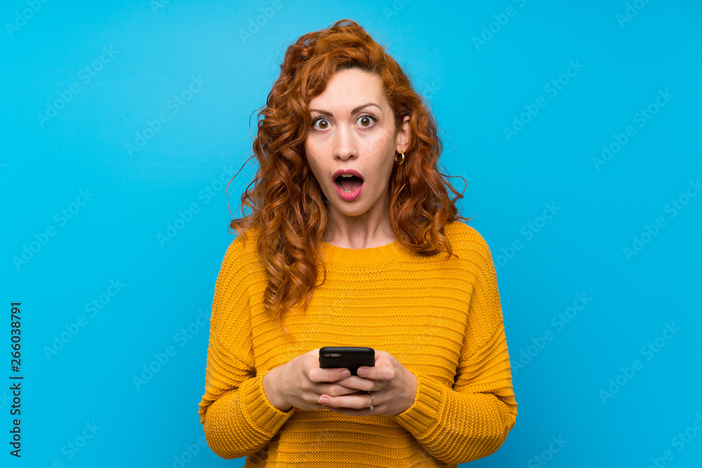 Redhead woman with yellow sweater surprised and sending a message Redhead woman with yellow sweater surprised and sending a message