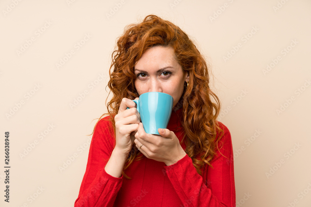 Redhead woman with turtleneck sweater holding hot cup of coffee Redhead woman with turtleneck sweater holding hot cup of coffee