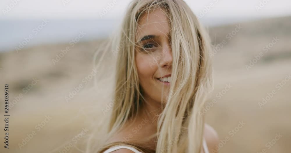 Beautiful young woman turns and smiles into the camera with her golden hair blowing in the wind, bohemian bride lifestyle Beautiful young woman turns and smiles into the camera with her golden hair blowing in the wind, bohemian bride lifestyle