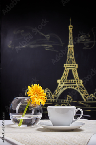 A Cup of coffee and bowl of gerberas on a background of graphite Board with the inscription "coffee". Parisian motifs.